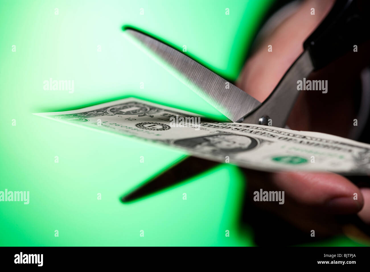Hand with scissors cutting US dollar bill Stock Photo
