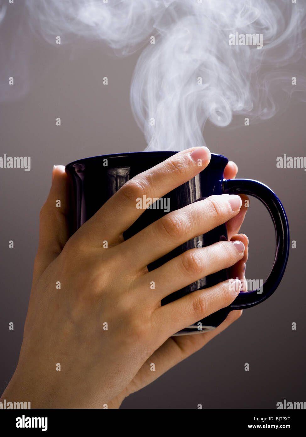 Hand holding hot cup of coffee Stock Photo