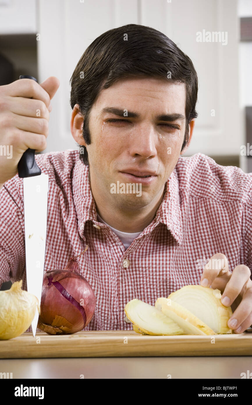 Man slicing onion and crying Stock Photo