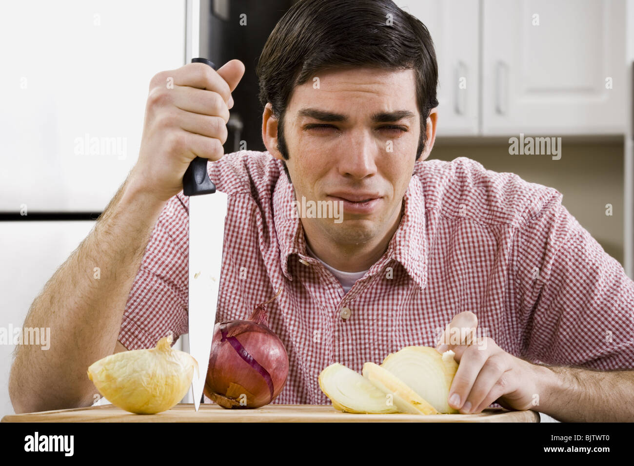 Man slicing onion and crying Stock Photo