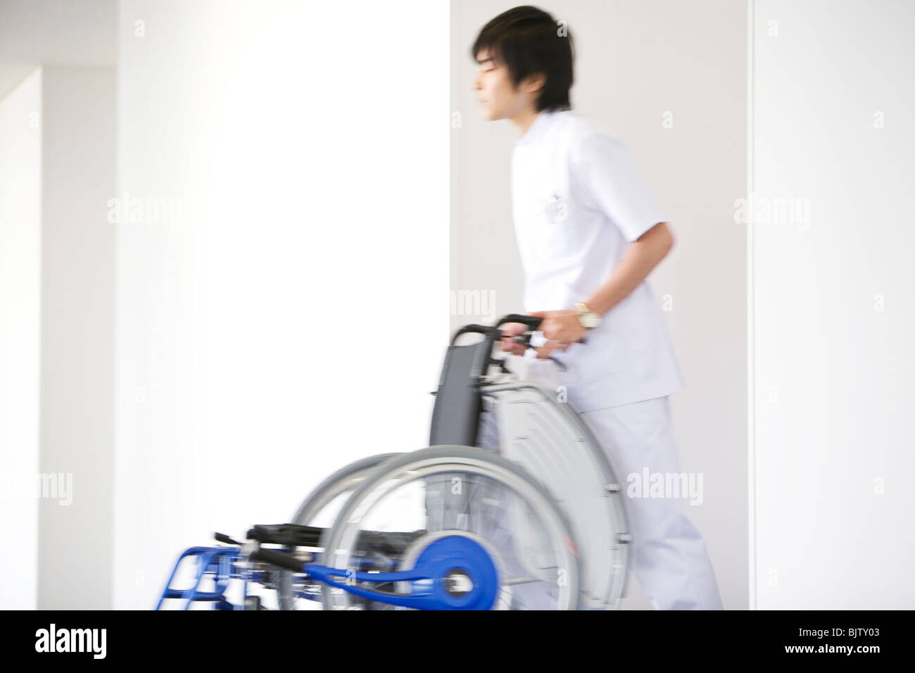 Orderly pushing wheelchair in hospital Stock Photo Alamy