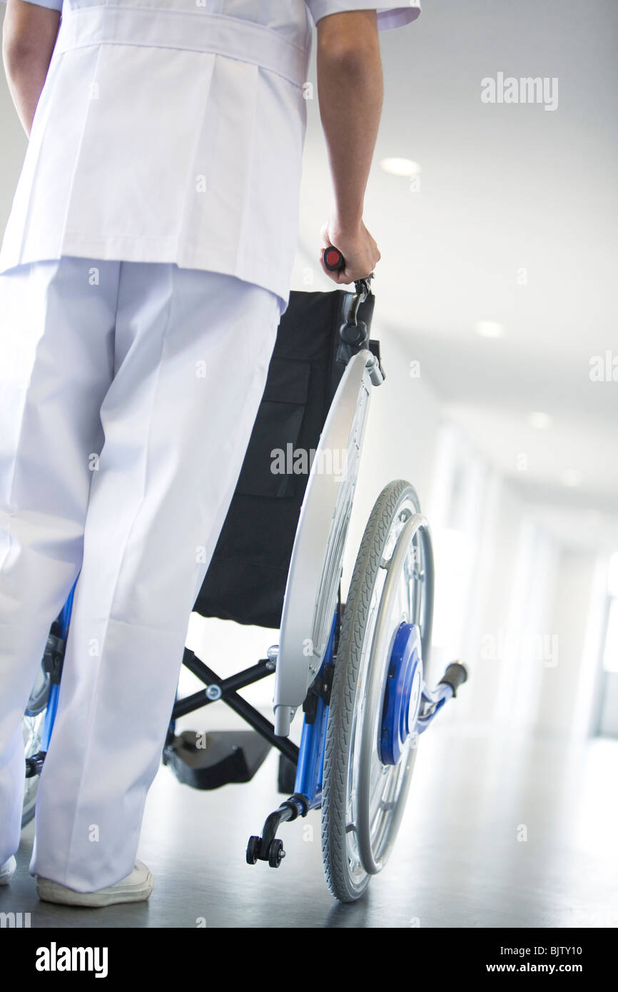 Orderly pushing wheelchair in hospital Stock Photo Alamy