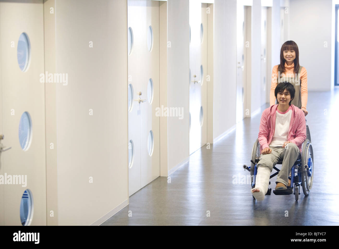 Woman pushing her boyfriend who is in a wheelchair Stock Photo - Alamy