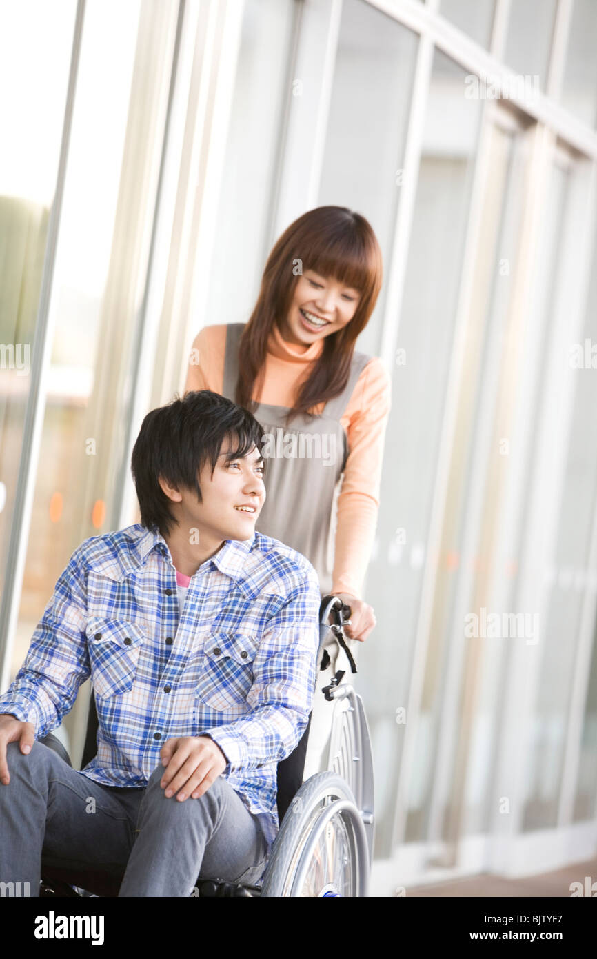 Woman pushing her boyfriend in a wheelchair Stock Photo - Alamy