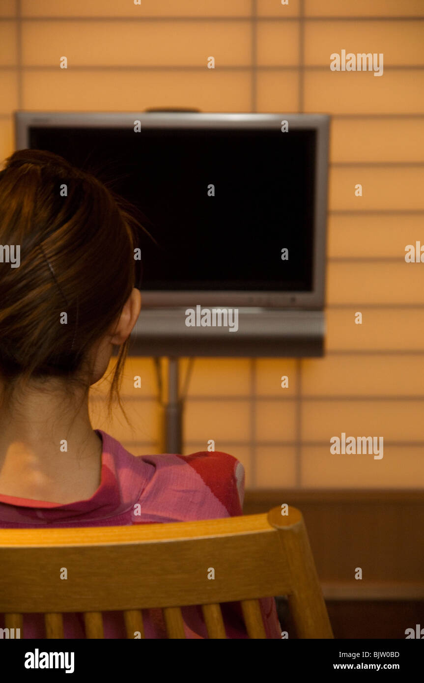 Woman wearing yukata looking at blank TV screen Stock Photo