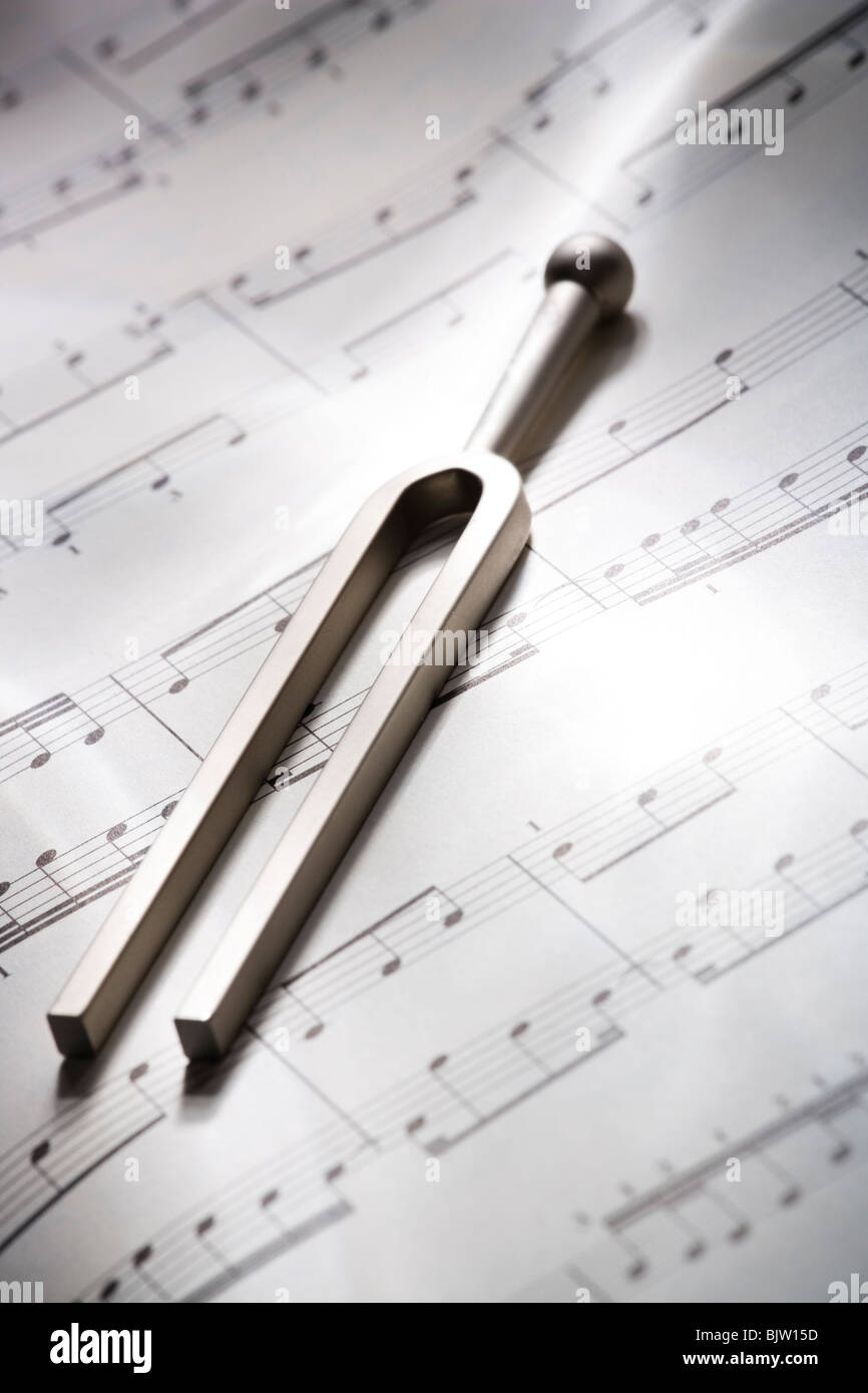 Tuning fork resting on musical score Stock Photo