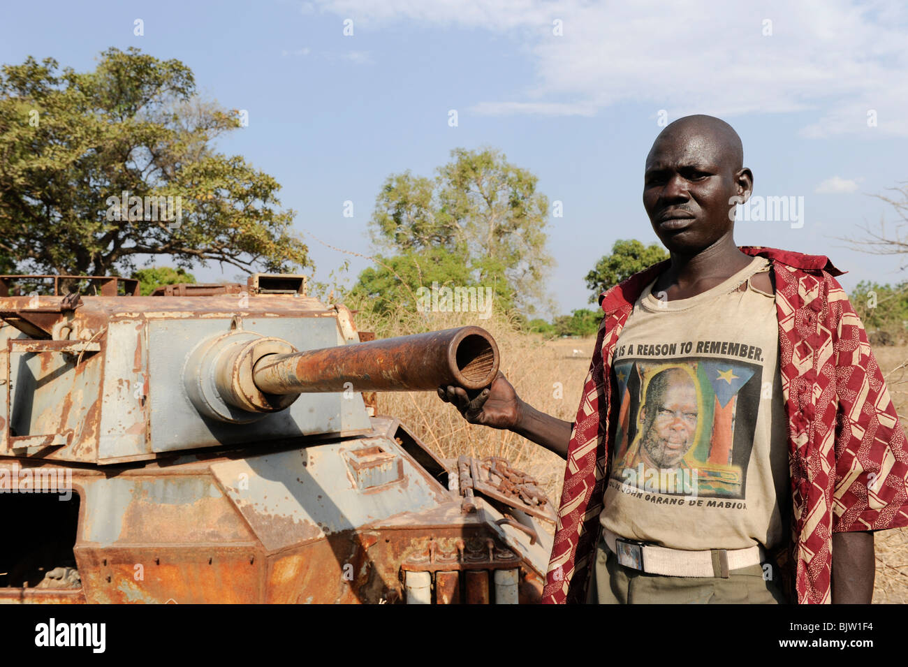 South Sudan, Rumbek , wreck of armoured car FV601 Saladin, captured by SPLA from SAF during civil war, man with T-Shirt former SPLA leader John Garang Stock Photo