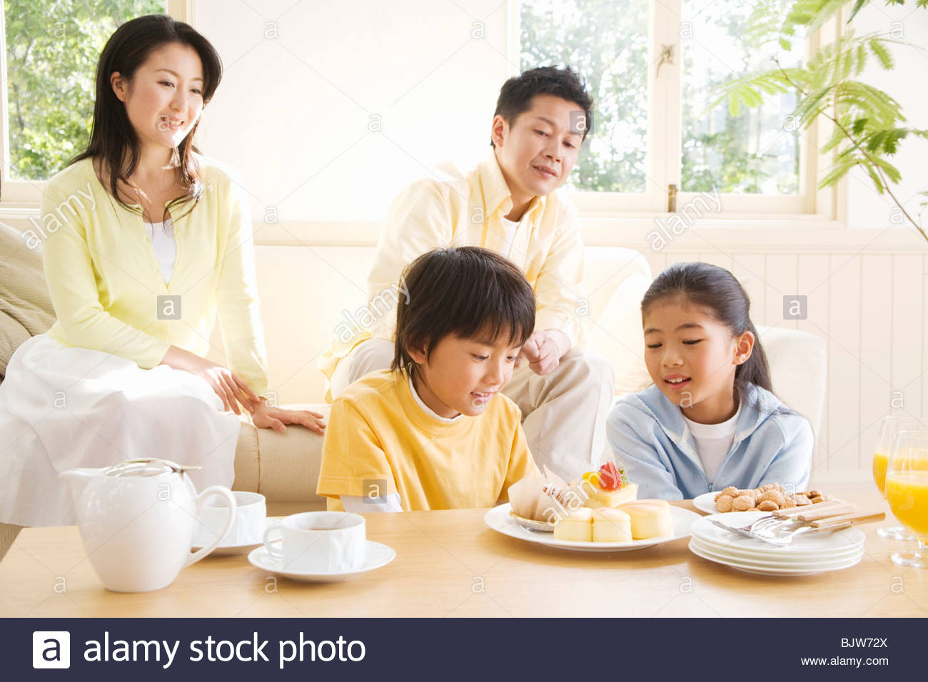 Happy Family Enjoying Afternoon Tea In Their Living Room