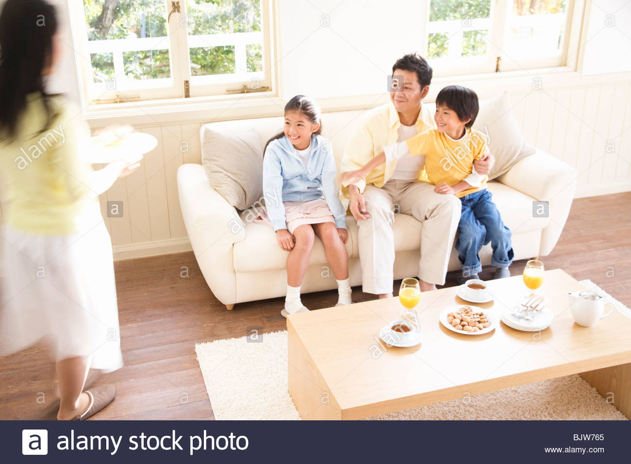 Happy Family Enjoying Afternoon Tea In Their Living Room