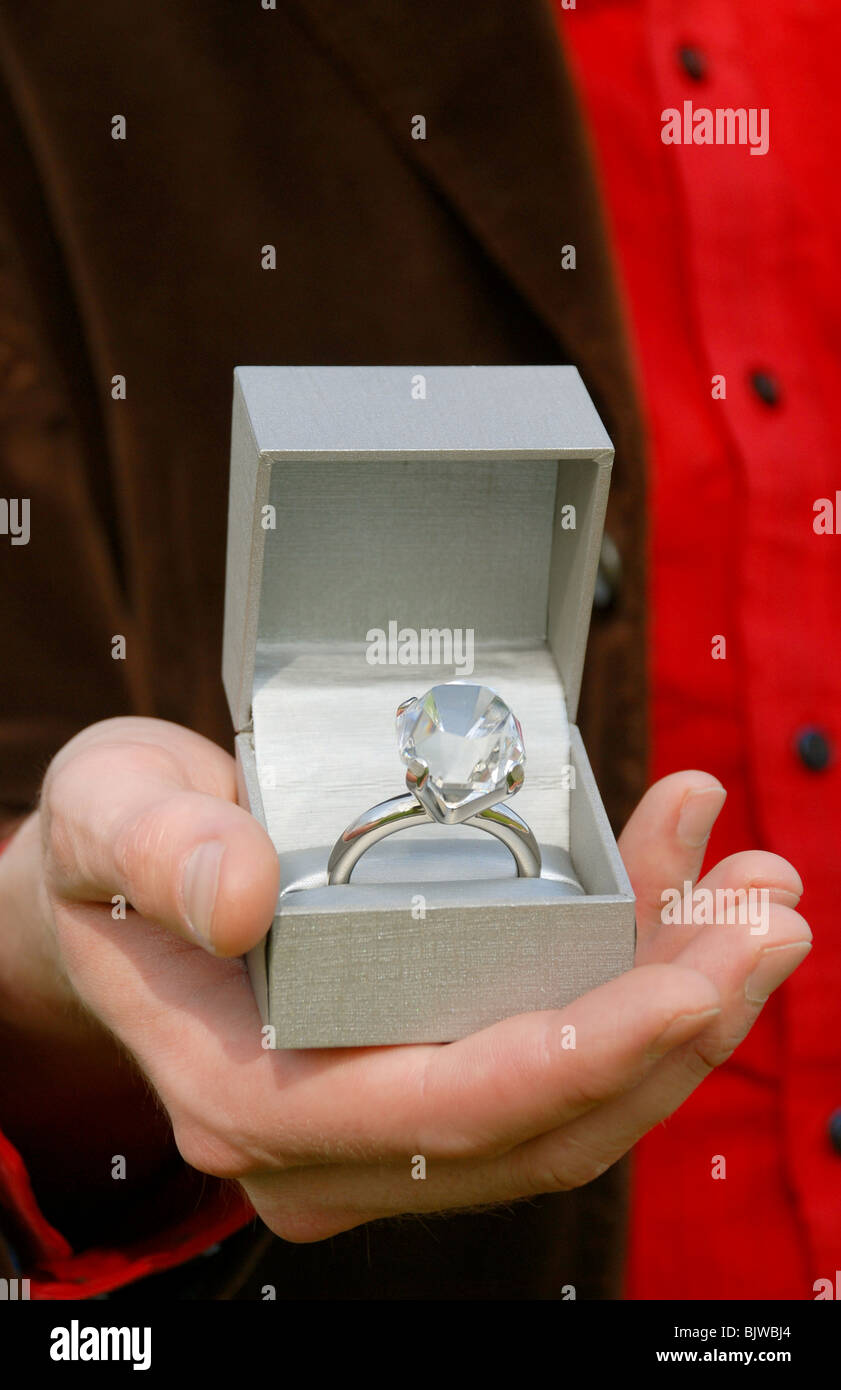 Man holding a box with an oversized diamond engagement ring inside. Stock Photo