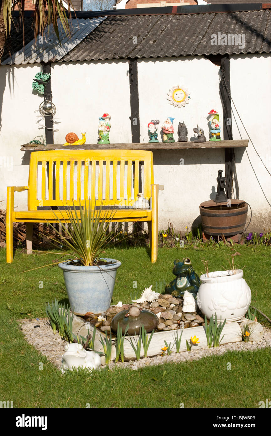 Yellow garden bench and ornaments and gnomes Stock Photo Alamy