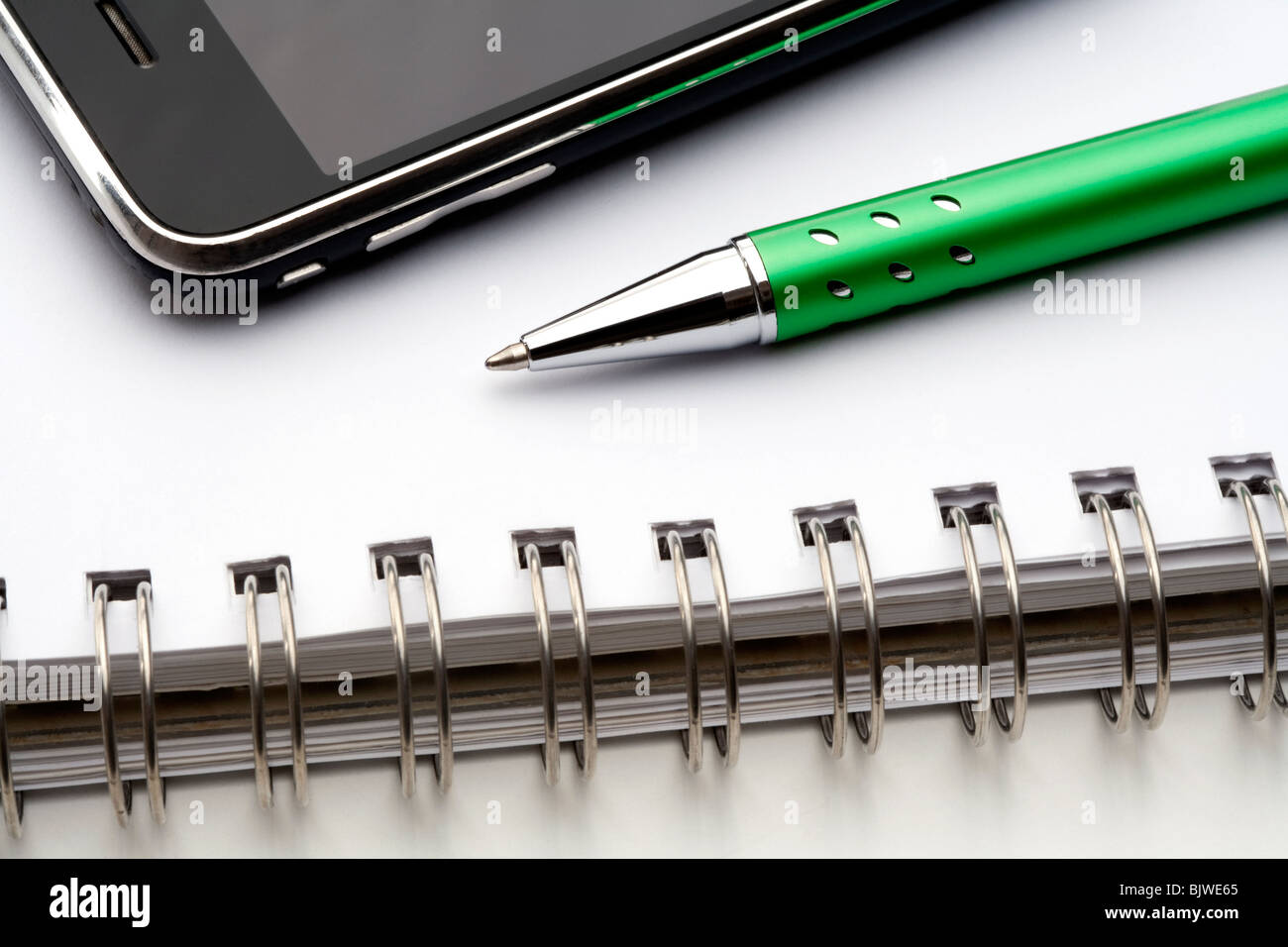 extreme closeup of a ballpoint pen, spiral notebook and cell phone Stock Photo