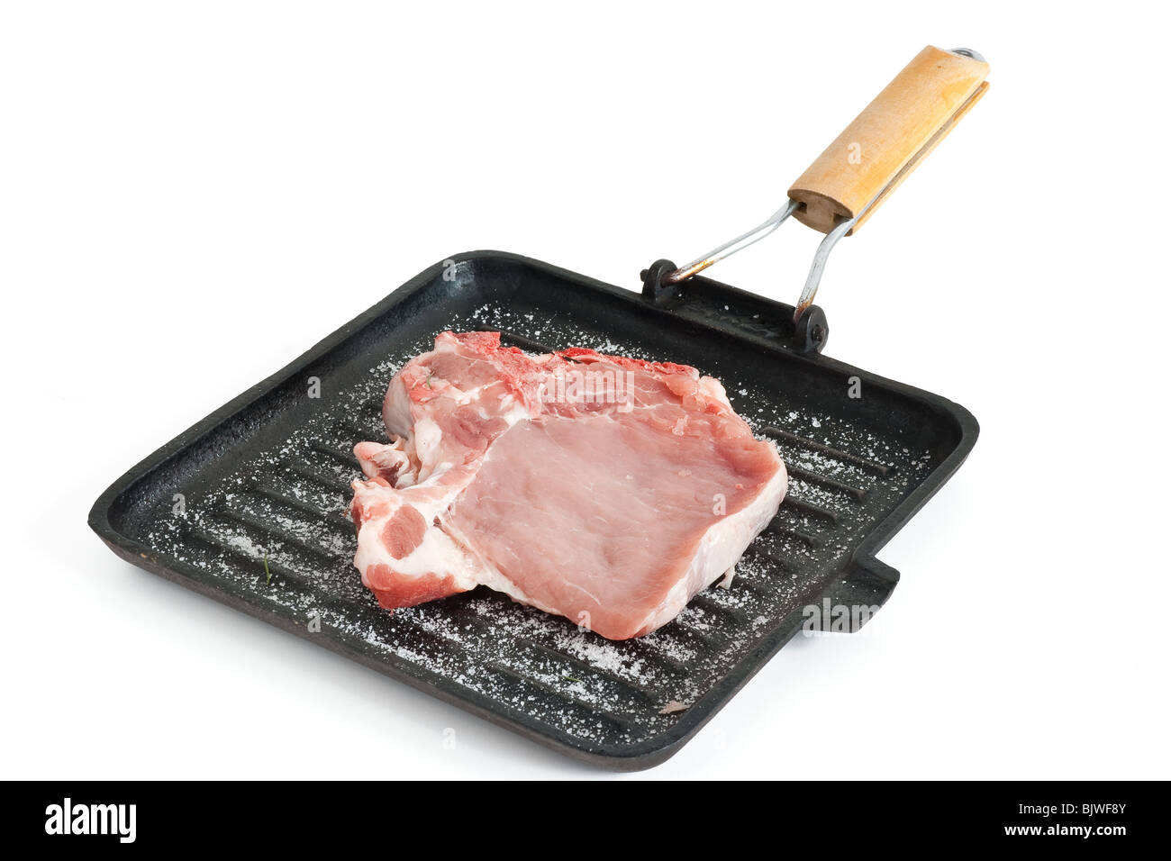 raw pork chop on a griddle with salt isolated on white background with clipping path Stock Photo