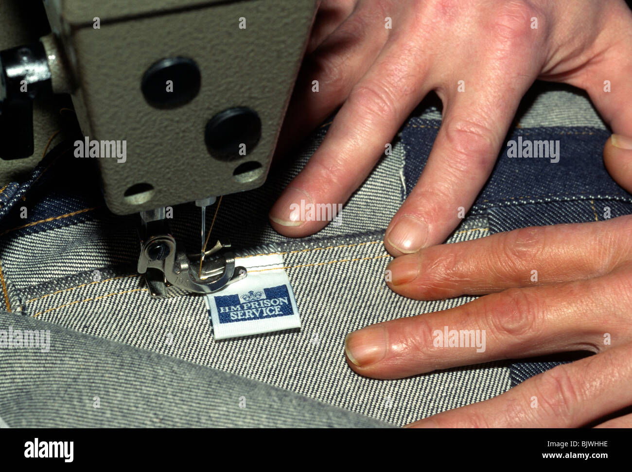 Sewing the label into a pair of prison regulation jeans, HM Prison Cardiff, Wales, UK. Stock Photo