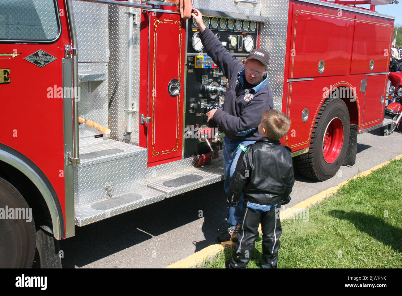 Firefighter showing young boy how a fire engine works USA by Dembinsky
