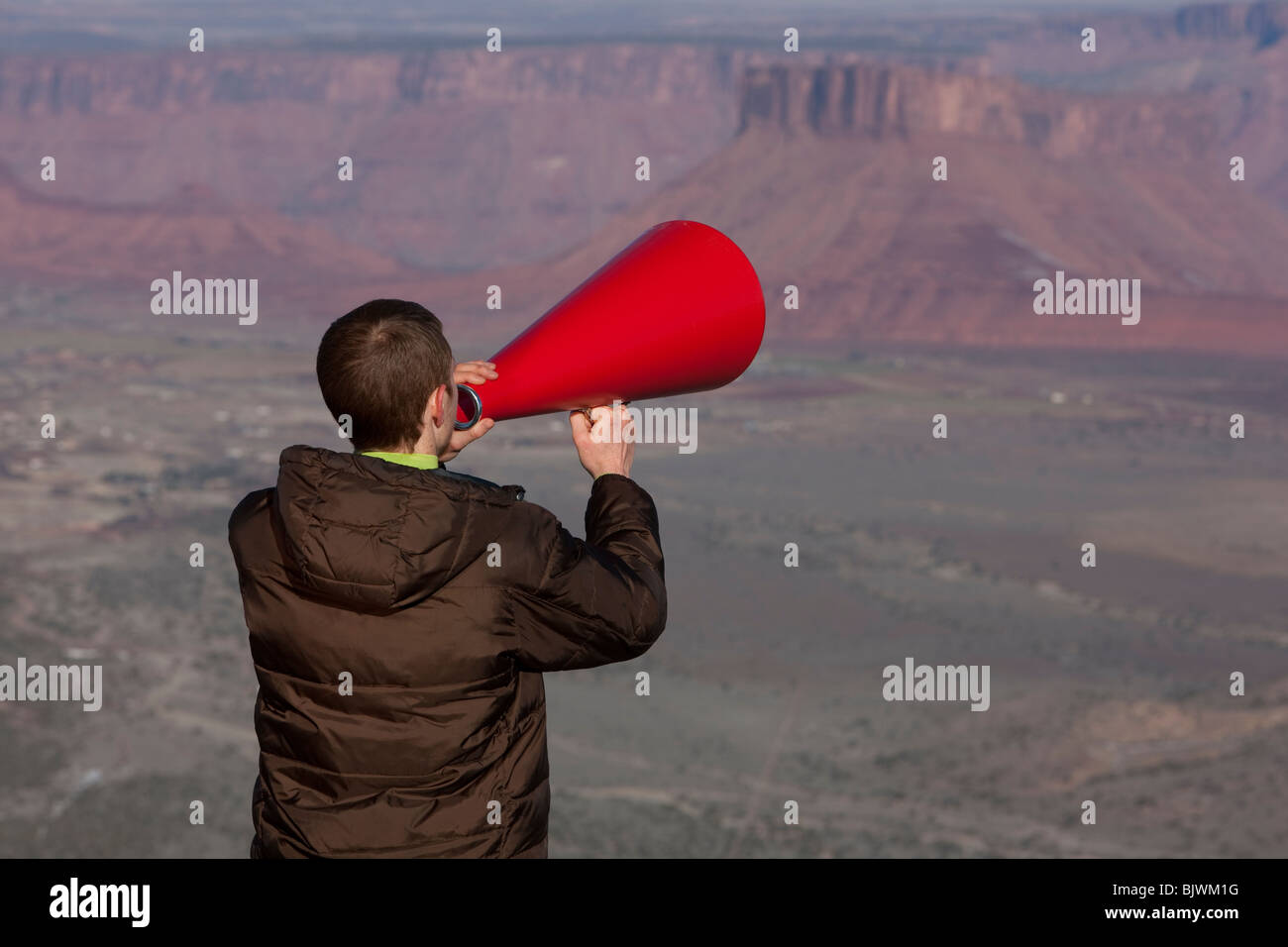 Man using megaphone at top of canyon Stock Photo
