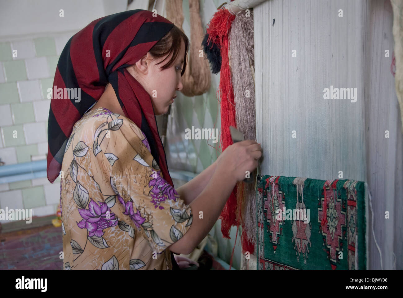 Young woman weaving a silk carpet in a Carpet Factory in Uzbekistan