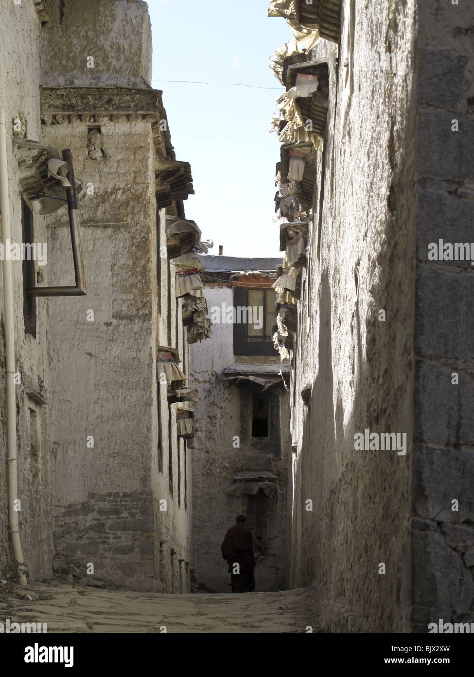 A Buddhist monk walks down the alley between two buildings at the Drepung Monastery in Lhasa, Tibet Stock Photo
