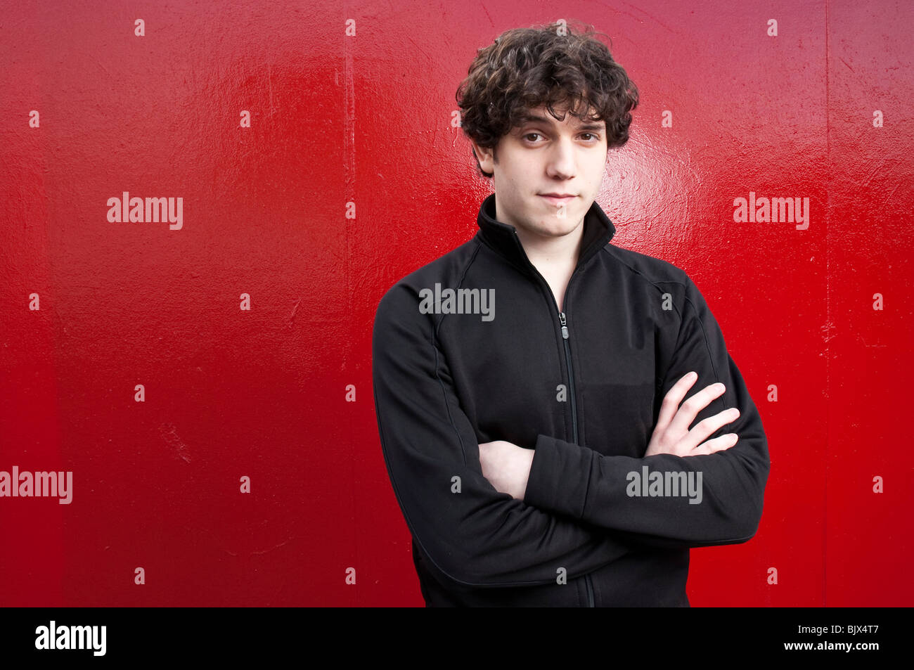 Portrait of young man looking into the camera with red background Stock ...