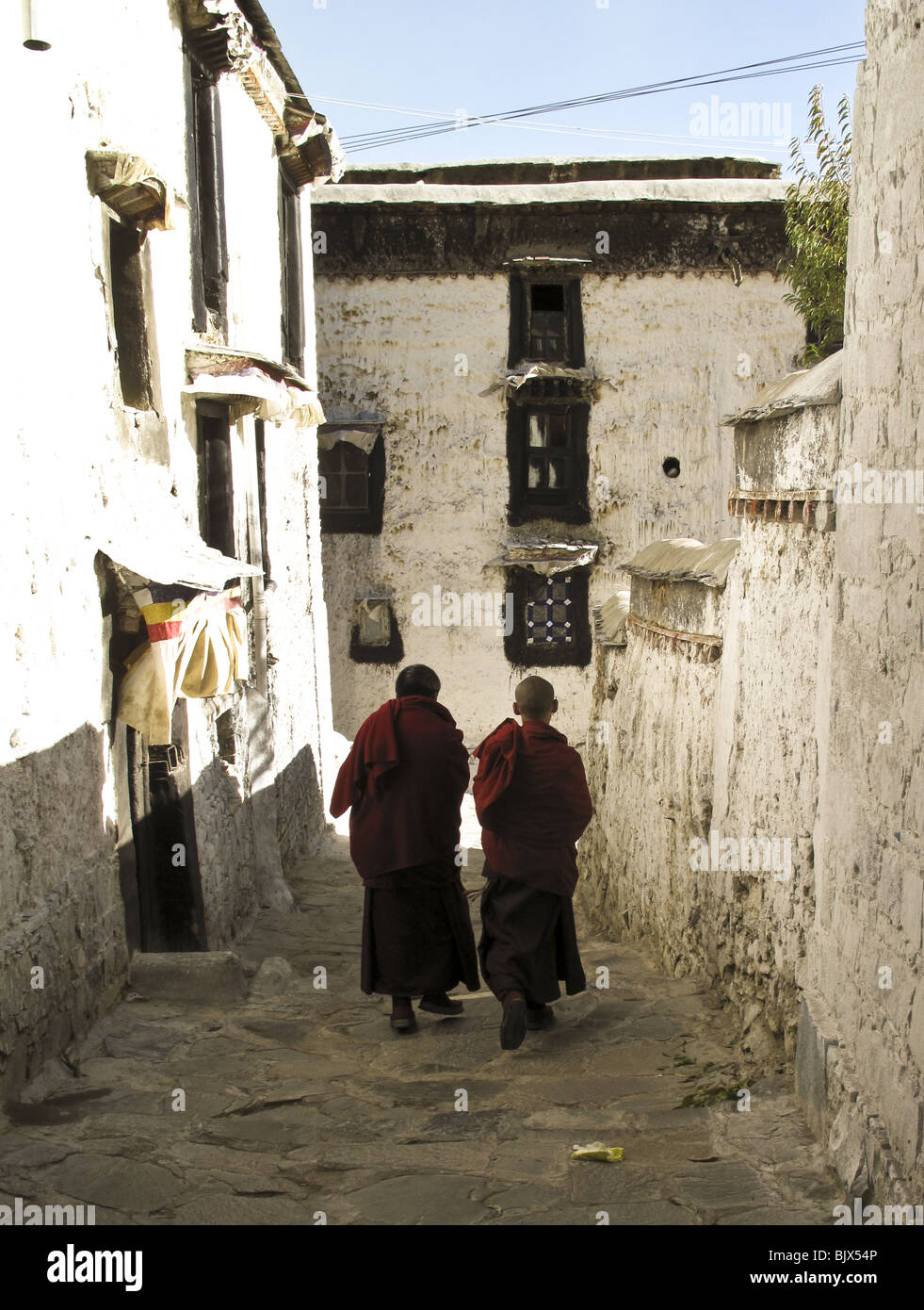 Two monks walk along the narrow walkways at the Drepung Monastery in Lhasa, Tibet Stock Photo