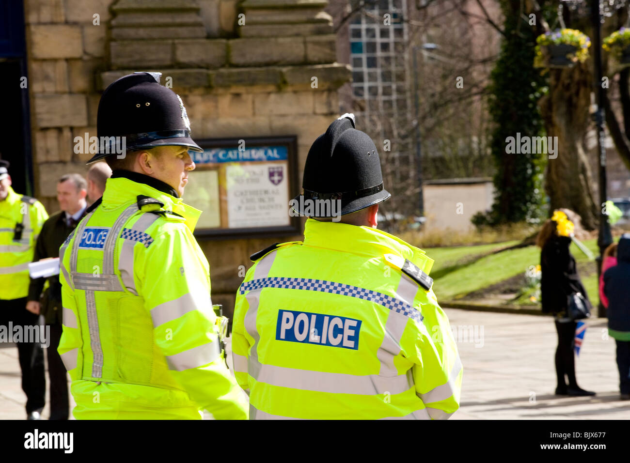 Two policemen stand guard to watch the crowd outside Derby Cathedral during The Queens visit for Maundy Thursday Easter. Stock Photo