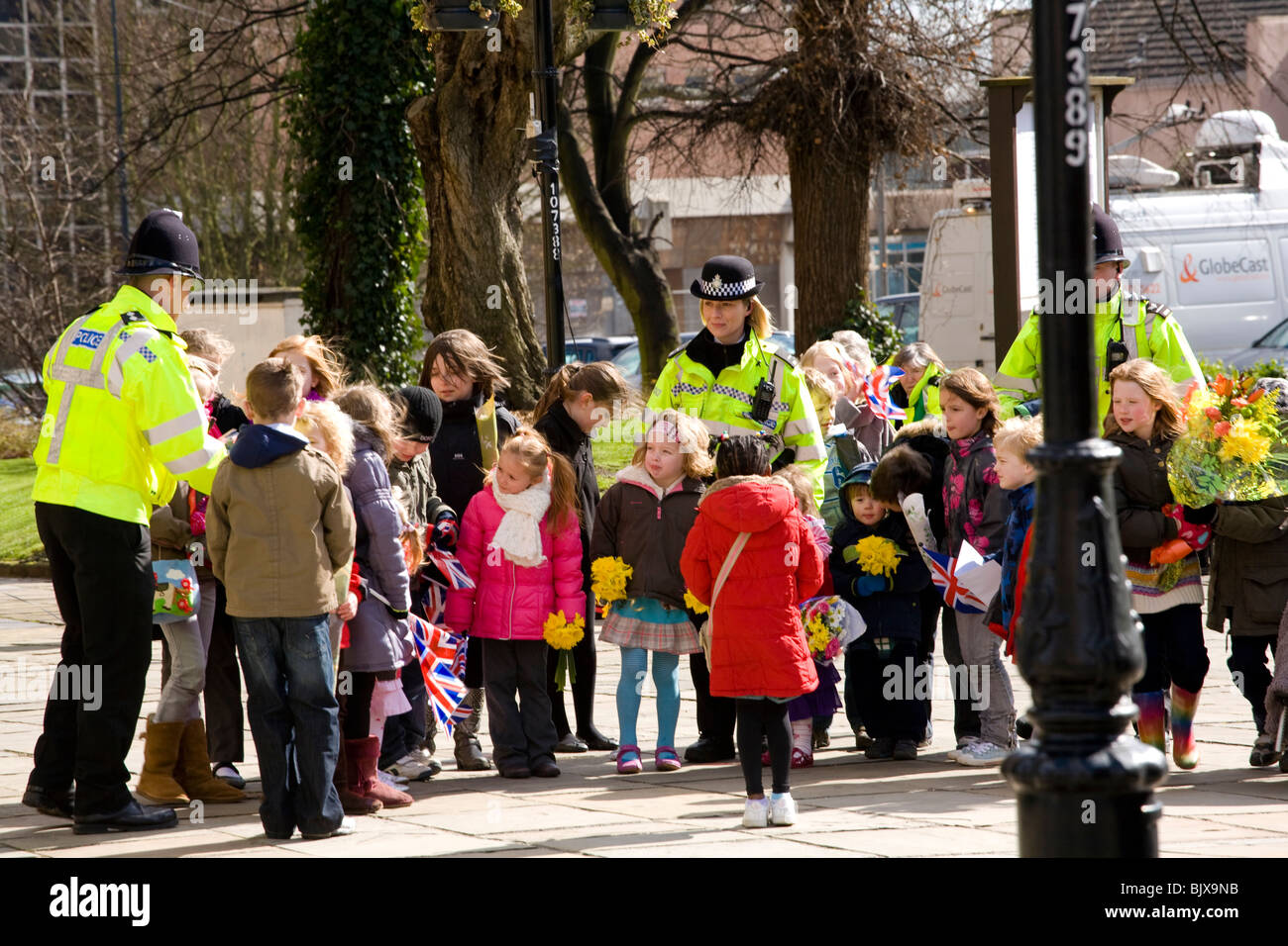Young children line up outside Derby Cathedral to meet the Queen after the Maundy Money ceremony, friendly police help. Stock Photo
