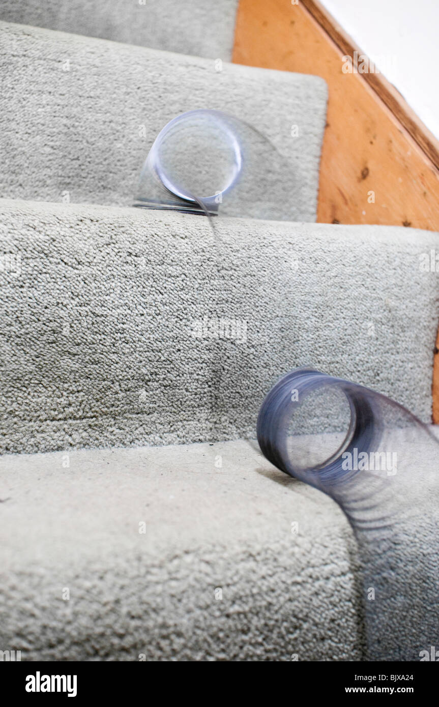 Slinky spring falling down carpeted stairs Stock Photo