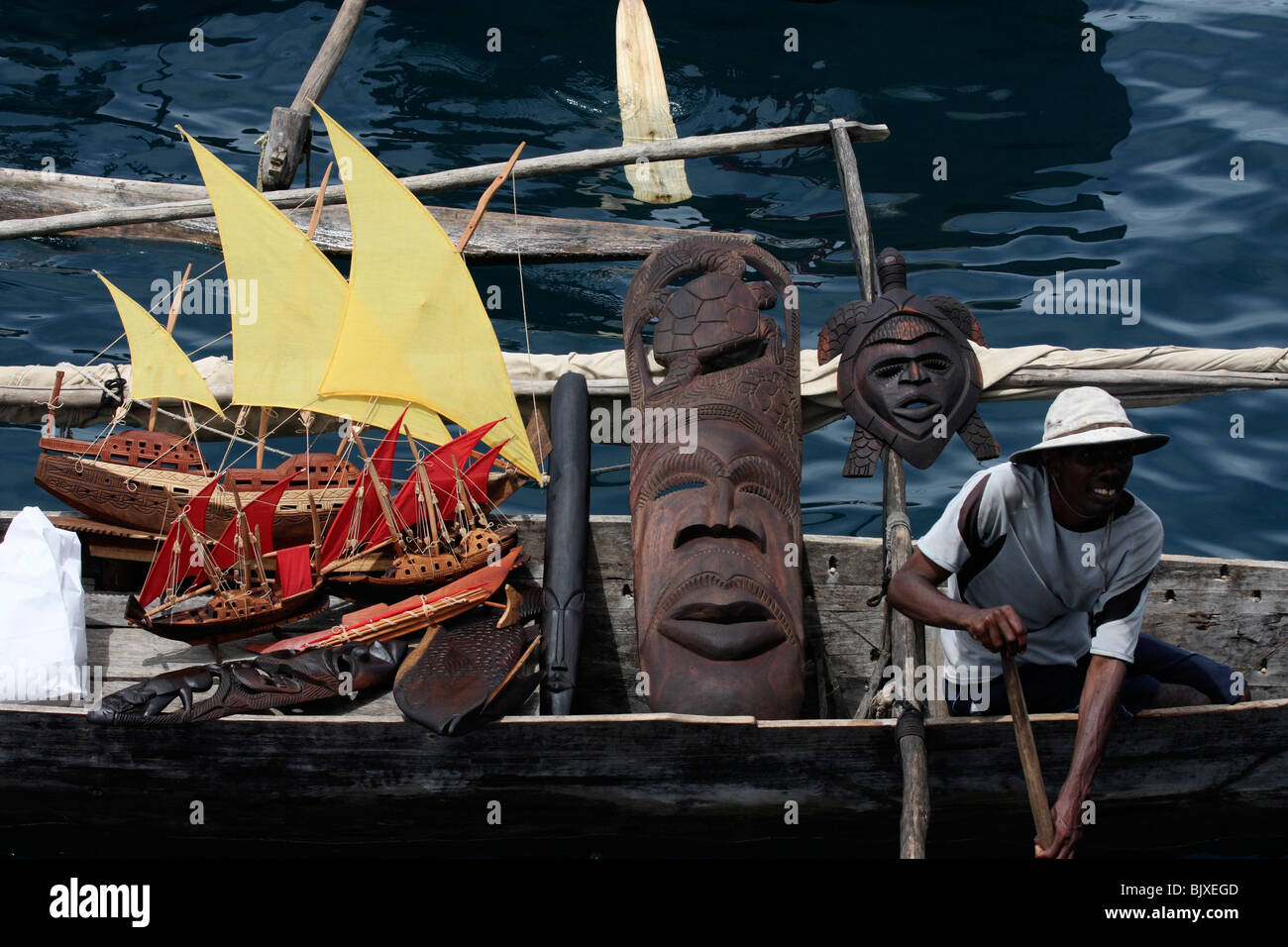 young poor african male in a boat with curios african sail boats,wooden masks and other suveniers for sale,madagascar,africa Stock Photo