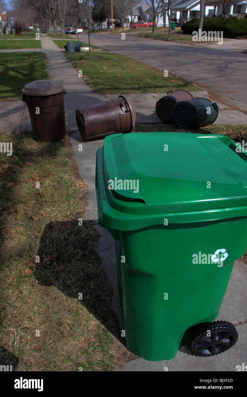 https://c8.alamy.com/comp/BJXF2D/green-recycling-bin-and-4-regular-plastic-trash-cans-on-sidewalk-next-BJXF2D.jpg