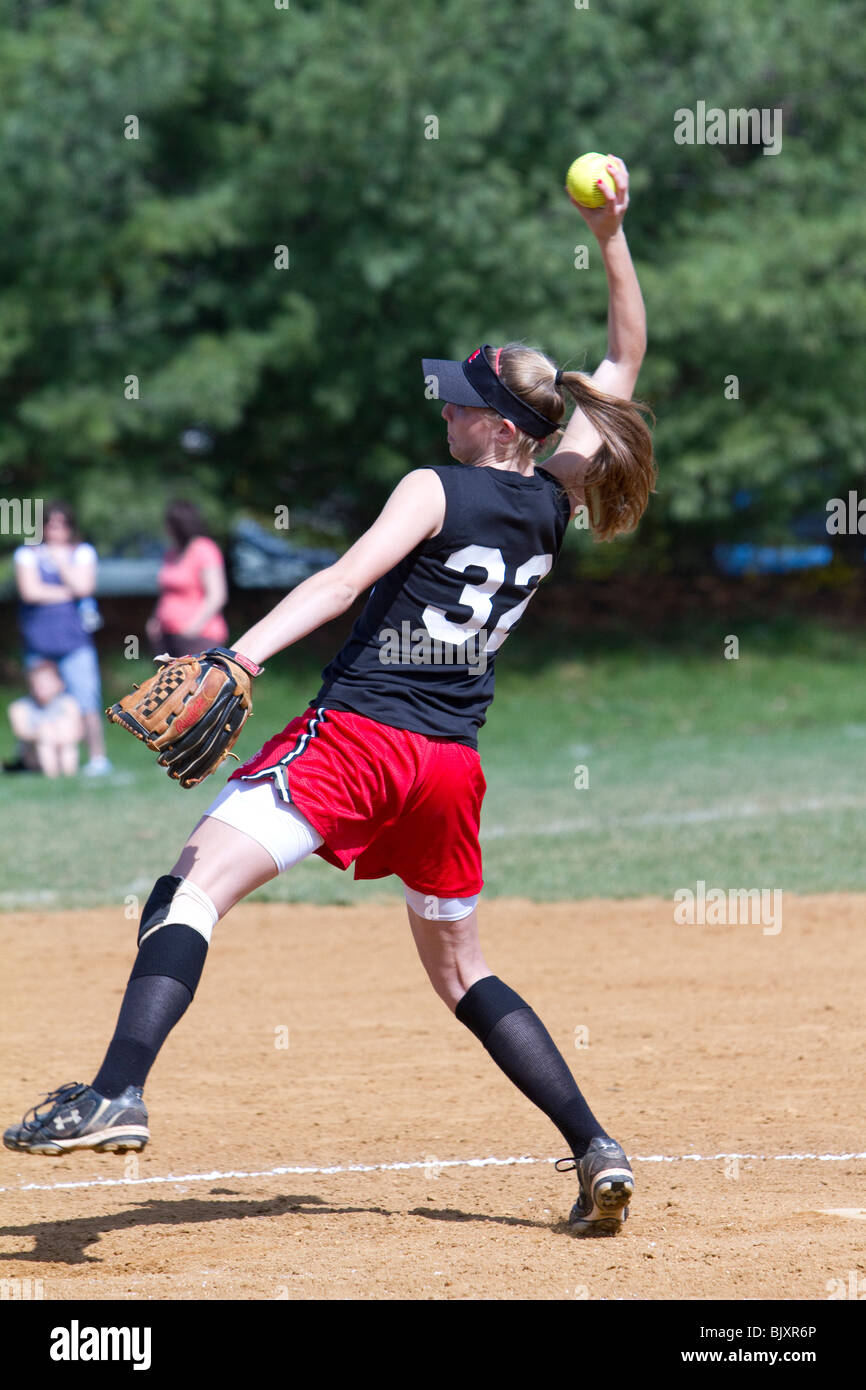 High kicking girls high school softball pitcher. Stock Photo