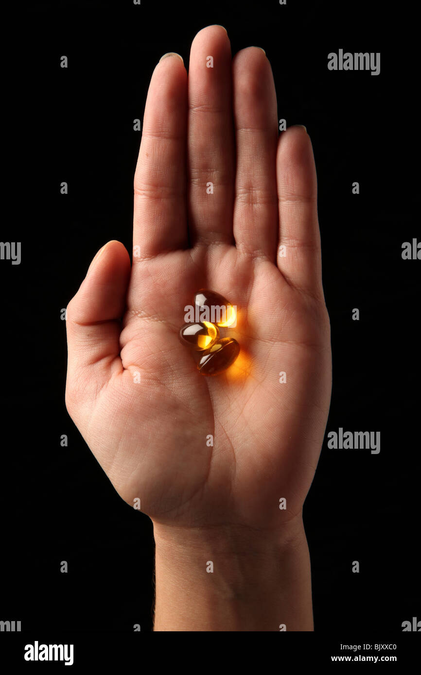 A female woman's hand holding three pills in the palm of her hand Stock Photo