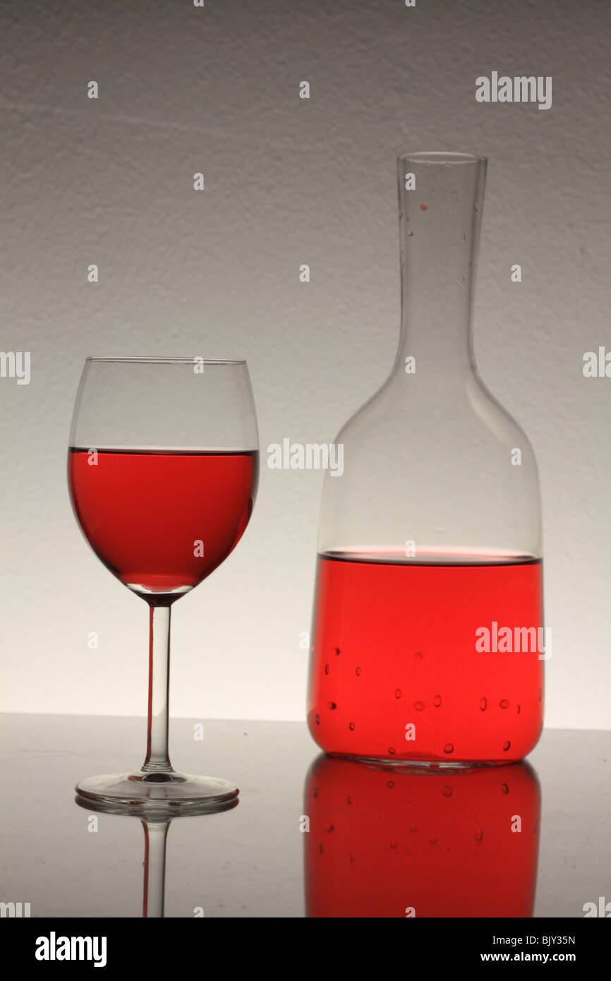 wine glass with red wine and bottle on table with reflection Stock Photo