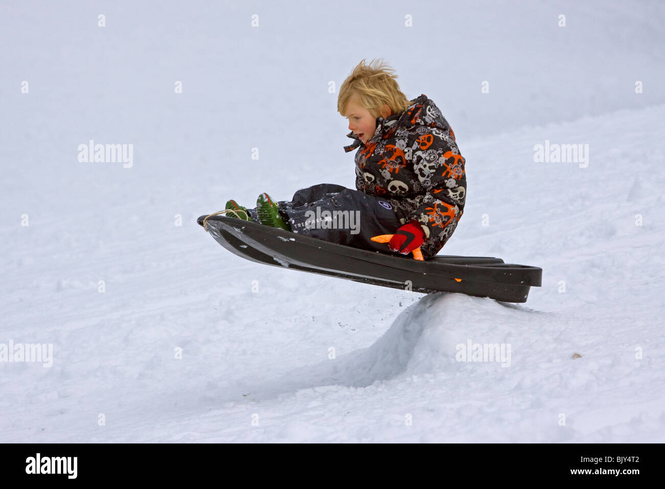 Sledging child playing snow winter play toboggan tobogganing Stock Photo