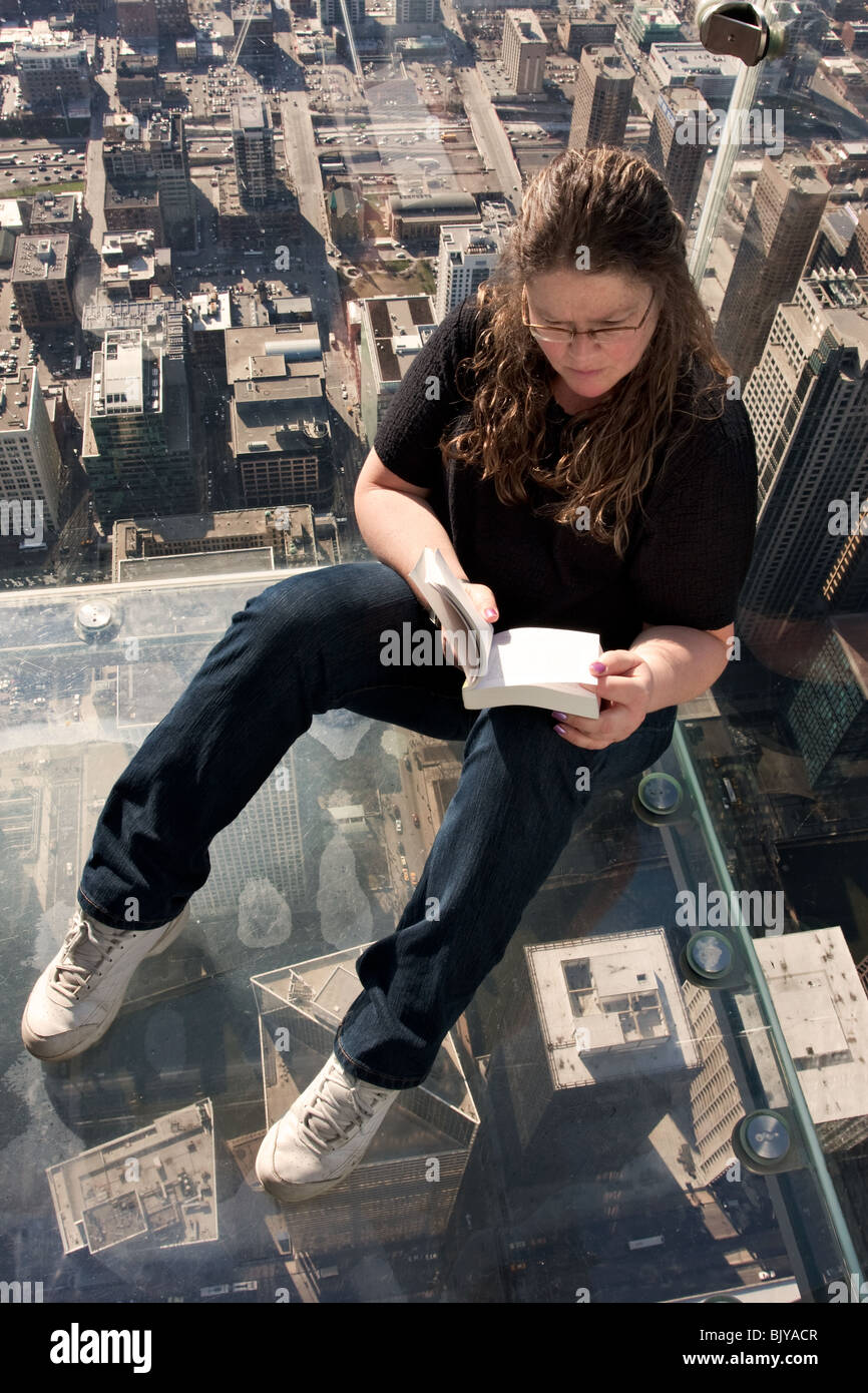 The ledge - Woman reading at the observation deck (skydeck) on top of the Willis (former Sears) tower in Chicago, Illinois, USA Stock Photo