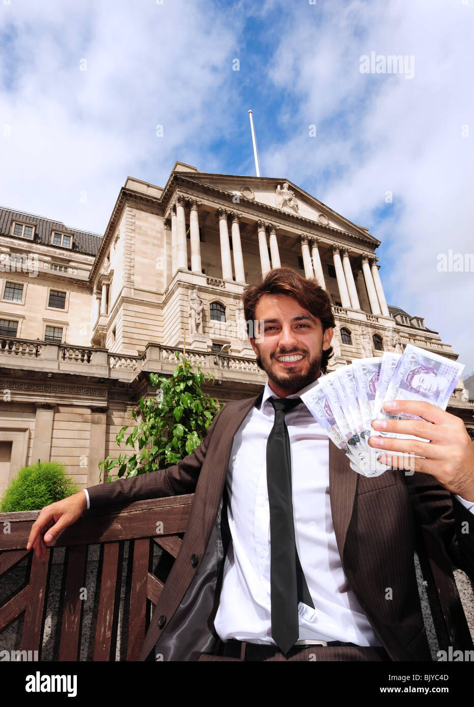 Vertical view of a business man holding twenty pound banknotes outside the Bank Of England in London England Stock Photo