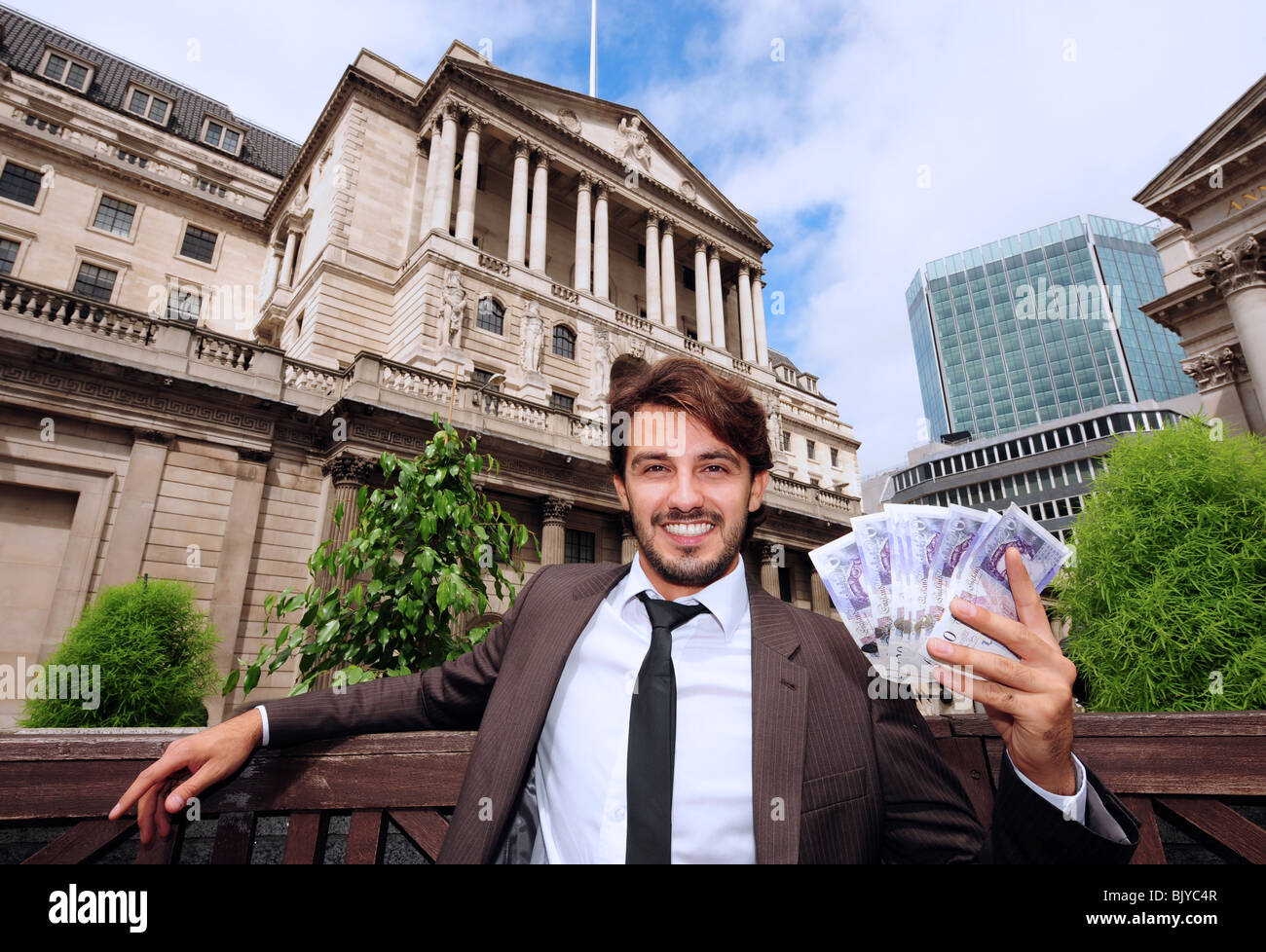 Horizontal view of a business man outside the Bank Of England in London England holding twenty pound banknotes Stock Photo
