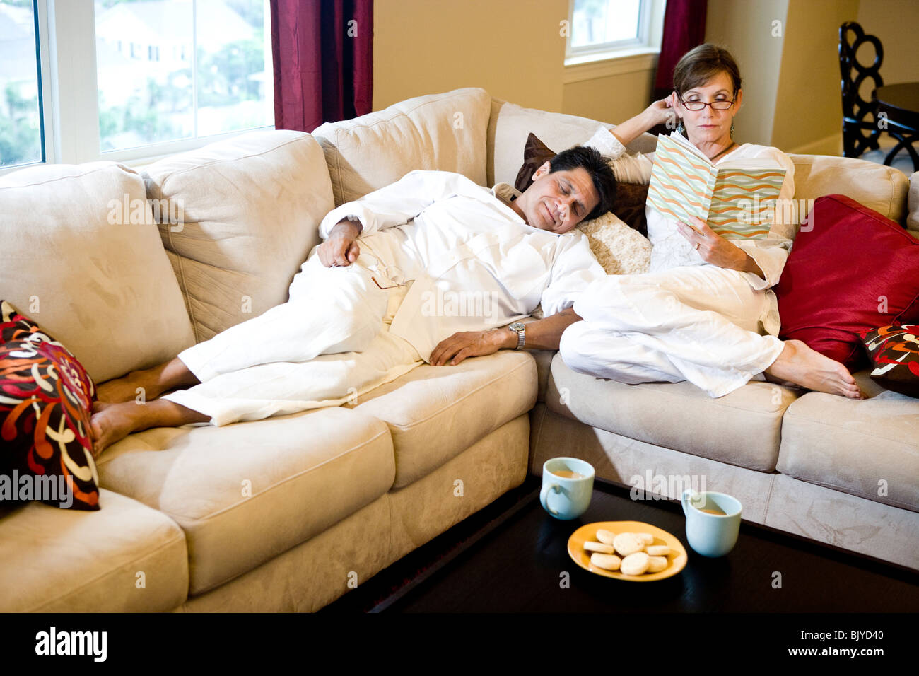 Happy middle-aged couple lounging on sofa at home Stock Photo