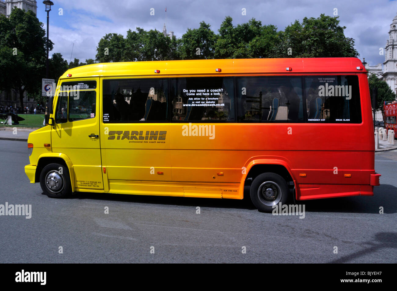 Side view of Starline minibus coach bus for private travel hire colourful paint job graduated from bright yellow to vivid red driving in London UK Stock Photo