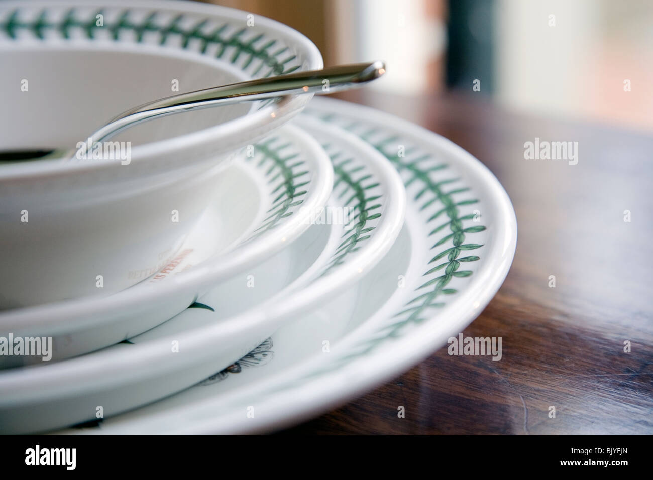 china dishes stacked on wooden table with spoon in bowl Stock Photo