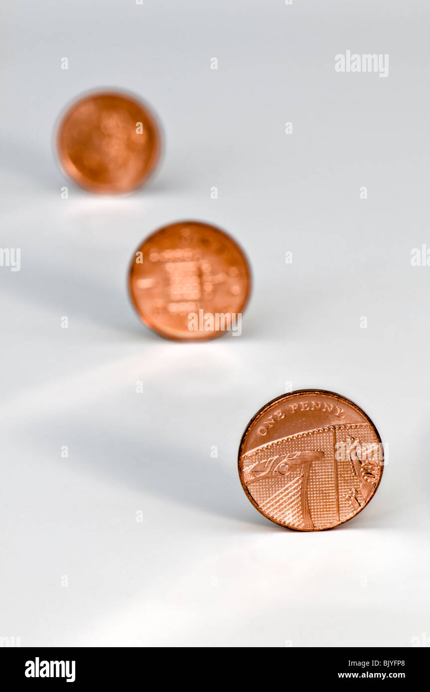 Three one penny pieces in diagonal line against a white background with the 2nd and 3rd coins out of focus Stock Photo