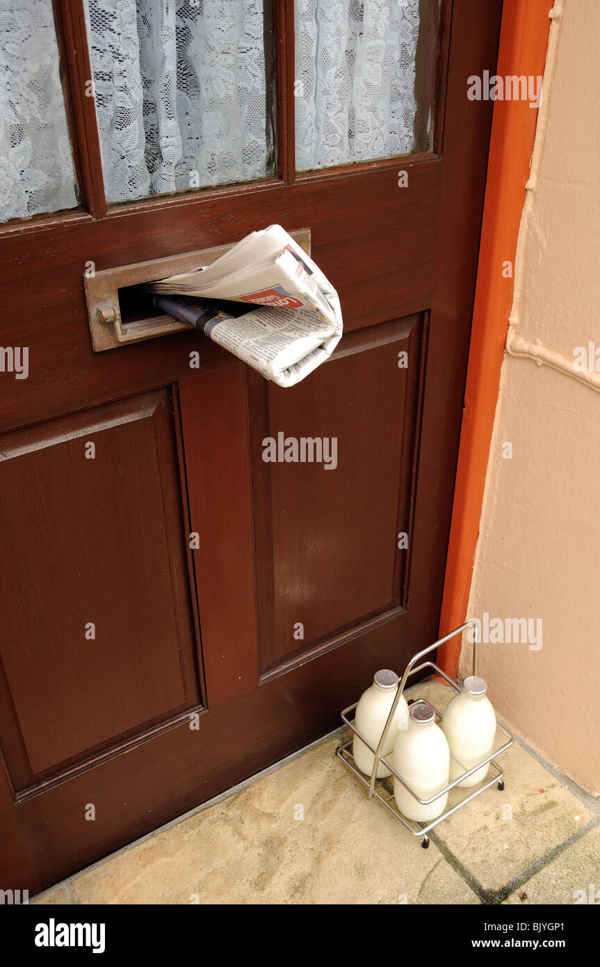 a newspaper in letterbox and milk delivery on doorstep, uk Stock Photo