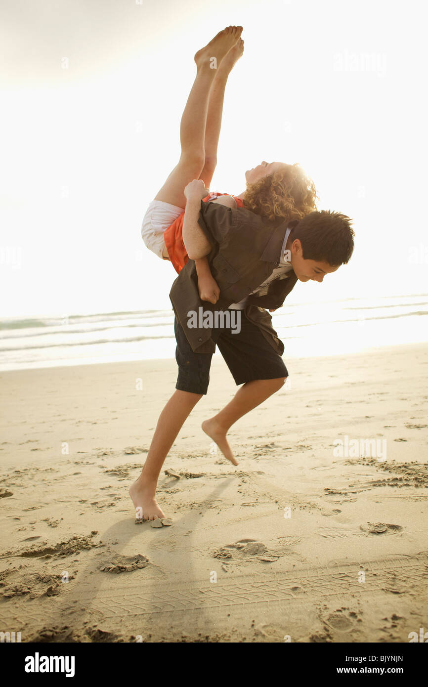 Boy lifting girl on back on beach Stock Photo - Alamy