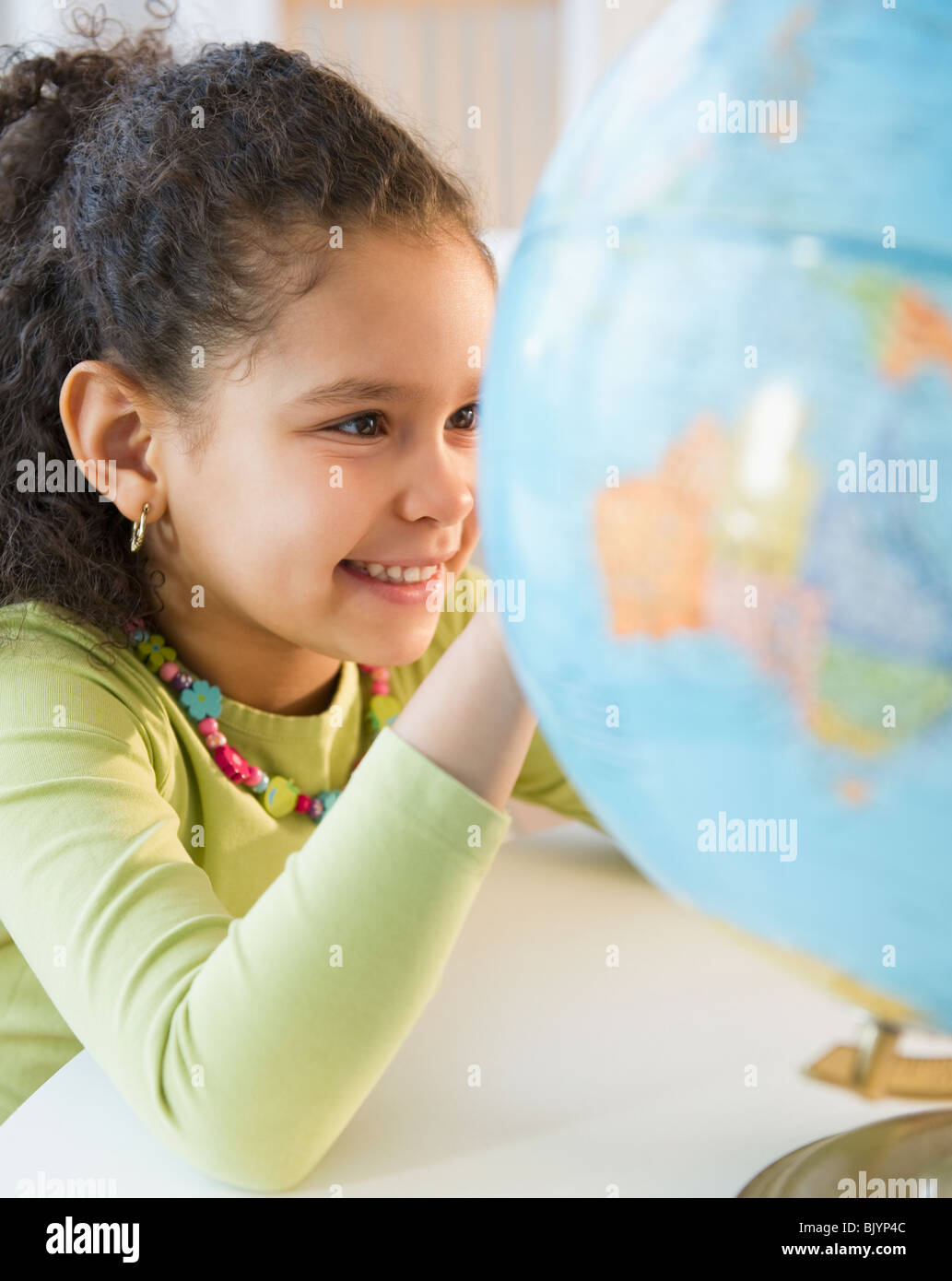 Hispanic girl looking at globe Stock Photo