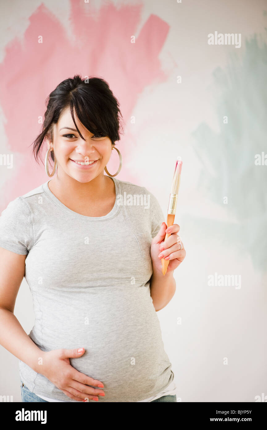 Pregnant Hispanic woman painting wall Stock Photo Alamy