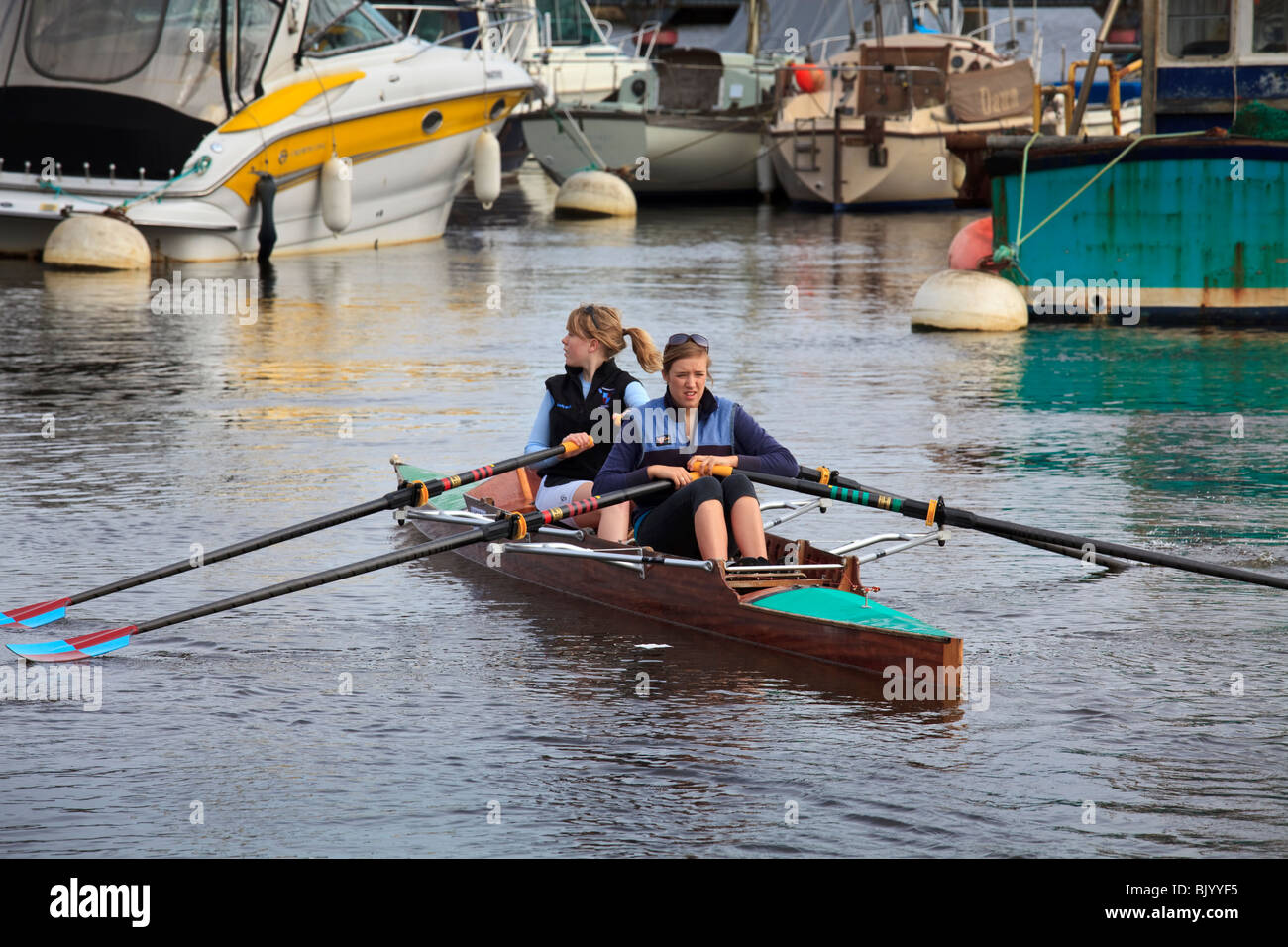 two female rowers in a skull in a marina looking for a way out Stock Photo