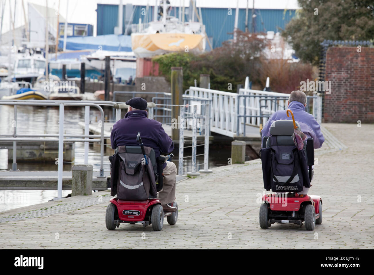 Two men in motorised wheelchairs on quay at Lymington. Stock Photo