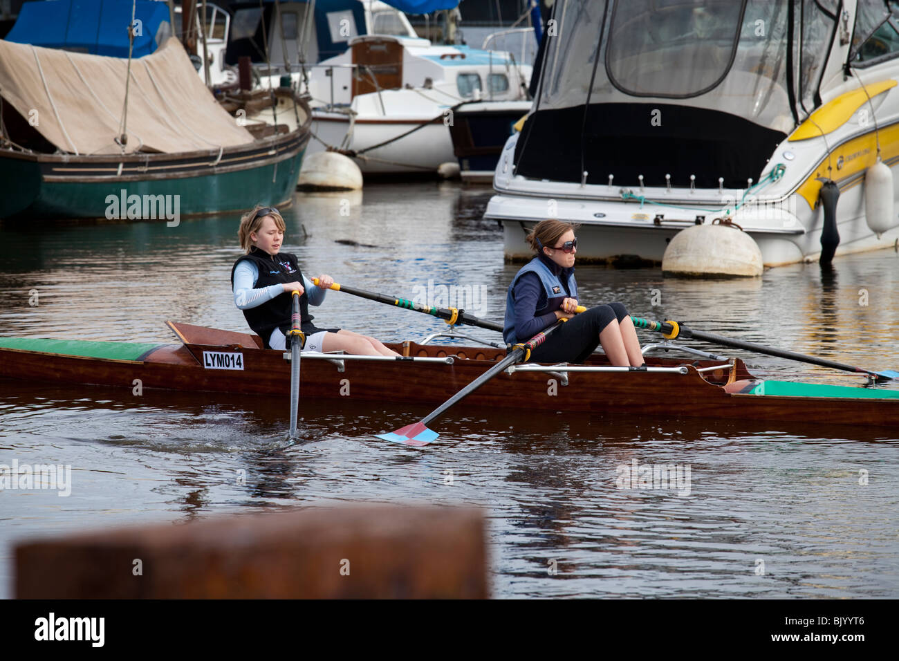 two female rowers in a skull in a marina looking for a way out Stock Photo