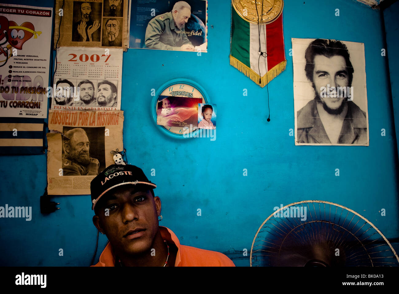 A Cuban watchmaker works in front of a wall covered by pictures of the Cuban Revolutionary leaders in Havana, Cuba. Stock Photo