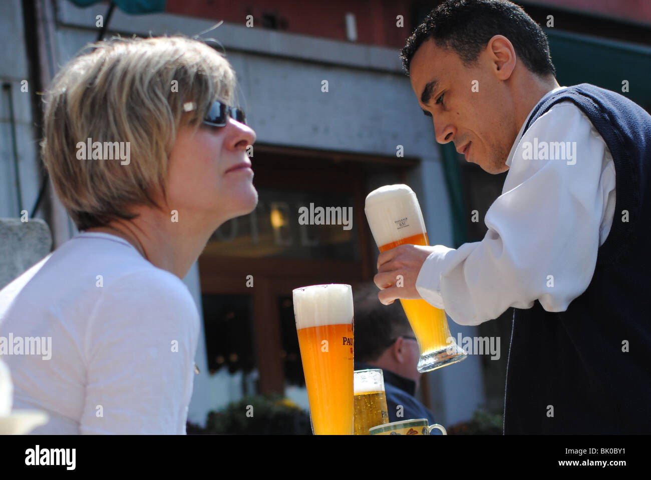 Waiter serving beer to tourists in a cafe, Venice, Italy Stock Photo