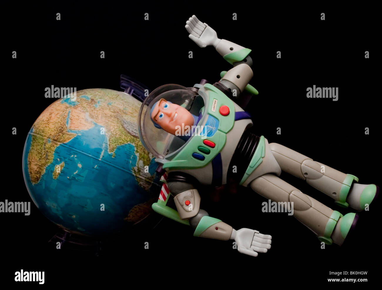 toy buzz lightyear held in front of the earth giving a concept of a space man floating in space Stock Photo
